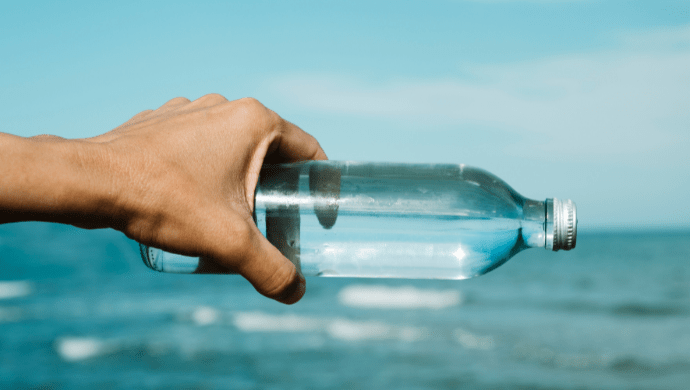 Water bottle with clear water, overlooking ocean. 